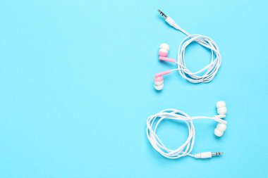 Mavi arka planda pembe ve beyaz kulaklıklar