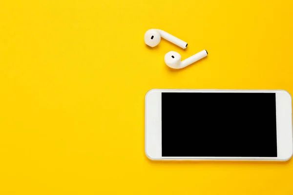 Bílé Bezdrátové Sluchátka Mobilním Telefonem Žlutém Pozadí — Stock fotografie