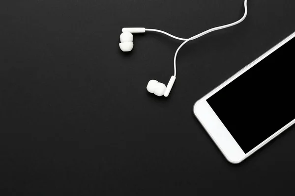 Earphones with mobile phone on black background