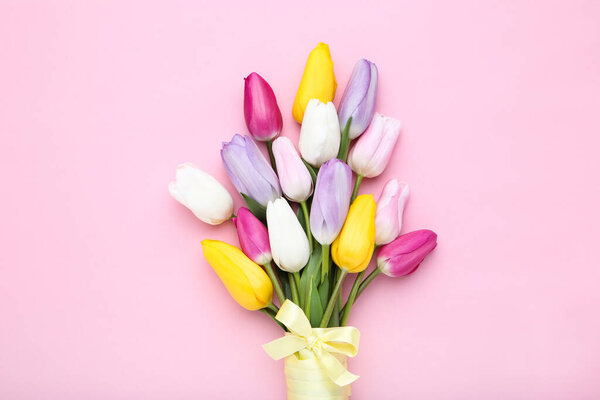 Bouquet of tulip flowers with ribbon on pink background