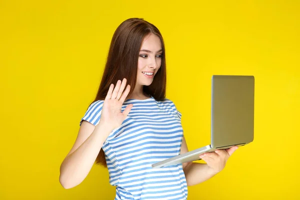 Tânăra Femeie Care Ține Computerul Laptop Flutură Mâna Fundal Galben — Fotografie, imagine de stoc