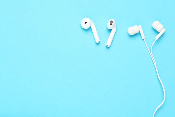 White earphones with wireless earbuds on blue background