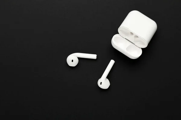 White wireless earphones on black background