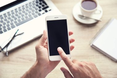 Bilgisayarlı cep telefonu, not defteri ve çay kullanan bir adam.
