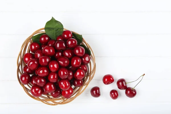Sweet cherries in basket on white wooden table