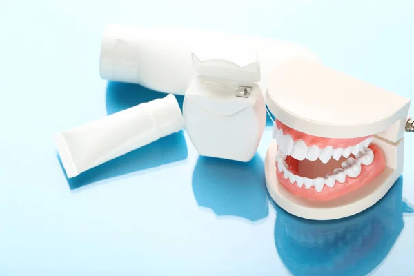 Model Zębów Butelkami Nitką Dentystyczną Niebieskim Tle — Zdjęcie stockowe