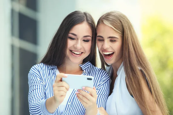 Twee Jonge Vrolijke Vriendinnen Die Mobiele Telefoon Straat Gebruiken — Stockfoto