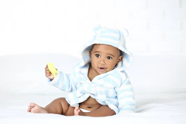 Bebê Americano Menina Roupão Sentado Cama Segurando Brinquedo — Fotografia de Stock