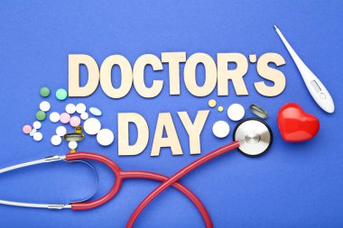 Stetoskop ve mavi arka planda renkli haplarla Doktorlar Günü 'nü yaz.