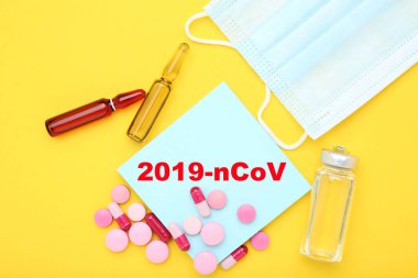 Coronavirus 'a sarı arka planda haplar, maske ve tıbbi ampullerle mesaj at