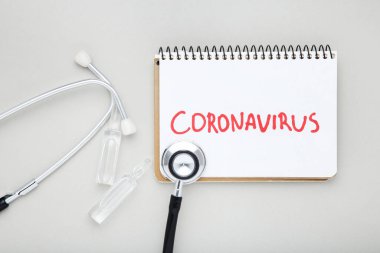 Coronavirus 'u tıbbi ampullerle ve gri arkaplanda steteskopla yaz.