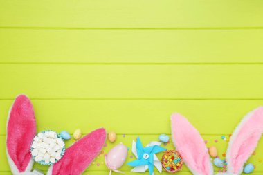 Paskalya konsepti. Tavşan kulaklı, yumurtalı, şekerli yeşil ahşap masa