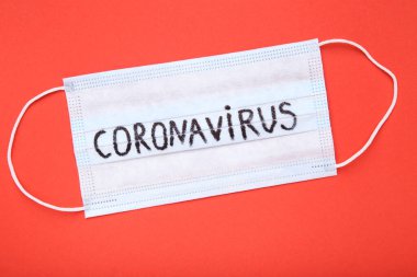 Kırmızı arkaplanda Coronavirus metni olan maske