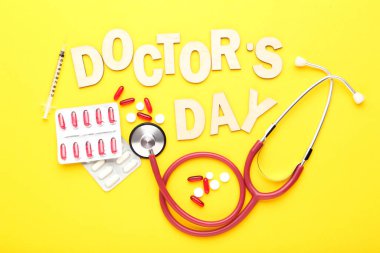 Stetoskop ve sarı arka planda renkli haplarla Doktorlar Günü 'nü yaz.