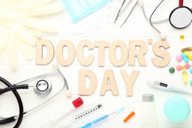 İlaç aletleri ve beyaz ahşap masada renkli haplarla Doktorlar Günü 'nü yaz.