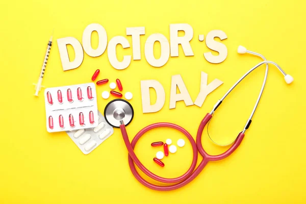 Ημέρα Του Γιατρού Κειμένου Στηθοσκόπιο Και Πολύχρωμα Χάπια Κίτρινο Φόντο — Φωτογραφία Αρχείου