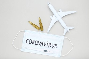 Coronavirus 'a tıbbi ampuller, termometre ve uçak modelini gri arka planda yaz