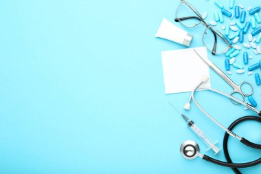 Mavi arka planda ilaç aletleri, haplar ve gözlüklerle Mutlu Doktor Günleri mesajı at.