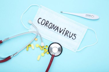Coronavirus 'a steteskop, termometre ve mavi arka planda haplarla mesaj at.