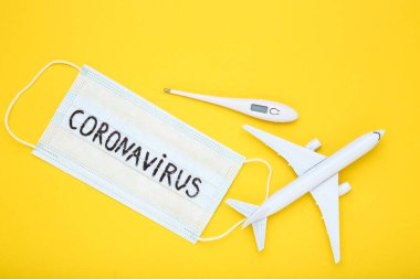 Sarı zemin üzerinde termometre ve uçak modeli olan Coronavirus 'a mesaj at