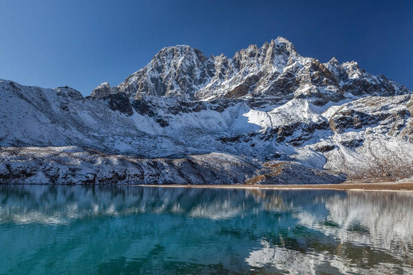 Amazingly beautiful Himalayan mountain range reflecting in the mirror surface of Gokyo Lake%27s transparent turquoise waters under the clear blue sky on a sunny day.