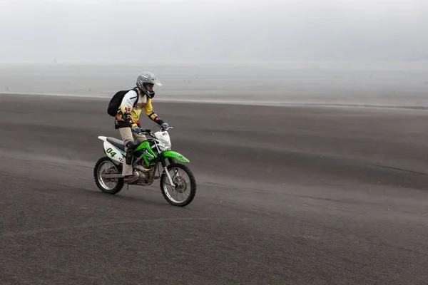 JAVA INDONESIA  Apr 19 2015 Tourist riding offroad bike through black ash sand dunes in Bromo