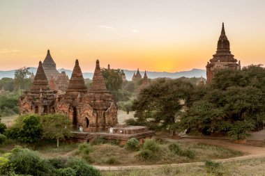 Eski Birmanya tapınakları ile yeşil ağaçlar günbatımında tuğla.