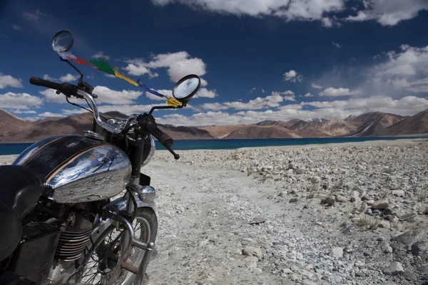 Vintage motorcycle on background of beautiful mountain lake Pangong lake in Ladakh by vintage