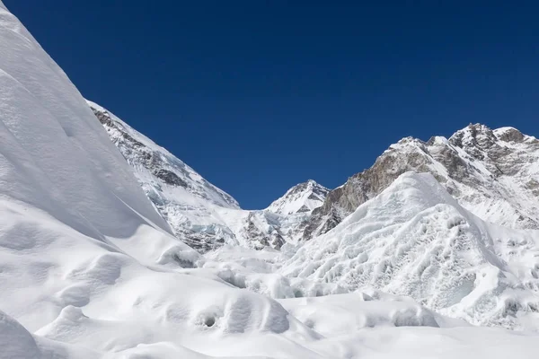 Schöne Schneeverwehungen und eisbedeckte Berge mit Blick auf die Gipfel und blauer Himmel mit weißen Wolken — Stockfoto