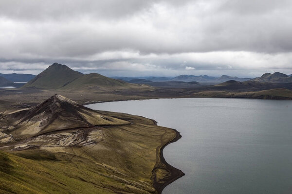 Dramatic Iceland scenery with big lake and green mountains covered with thick icelandic moss