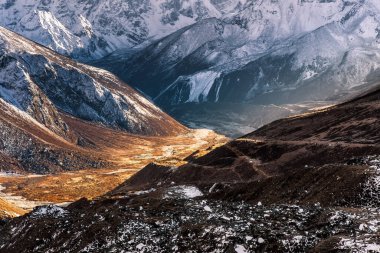 Abstract mountain background. Sunny valley among high snowy mountains on a bright sunny day. Himalayas mountains in Sagarmatha National Park, Nepal.. bold photo.