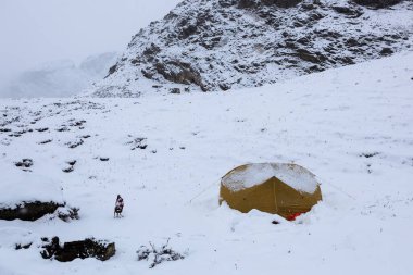 Kötü havada, karlı bir çadırda kamp yapmak. Dağlarda kamp yapmak. Soğuk ve karlı.