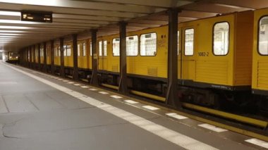 Berlin metrosunda iki sarı tren, aynı anda gelip gidiyor.