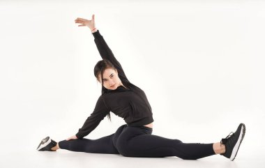 Genç atletik kadın yoga ve jimnastik yapıyor, esneme egzersizleri yapıyor, sicim üzerinde oturuyor beyazların üzerinde. 