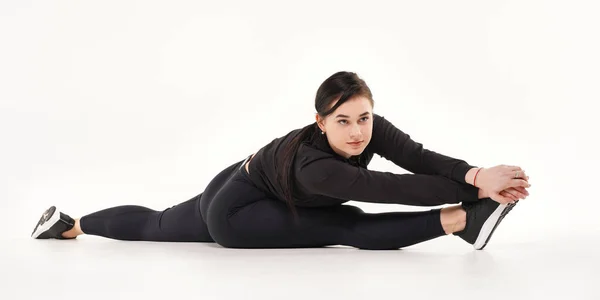 Ung atletisk kvinna som gör yoga och gymnastik stretching övningar, sitter på garn isolerad på vit — Stockfoto