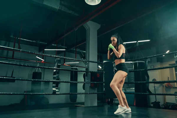 Mujer atlética de pie en el ring de boxeo preparado para la lucha con vendajes de boxeo en las manos —  Fotos de Stock