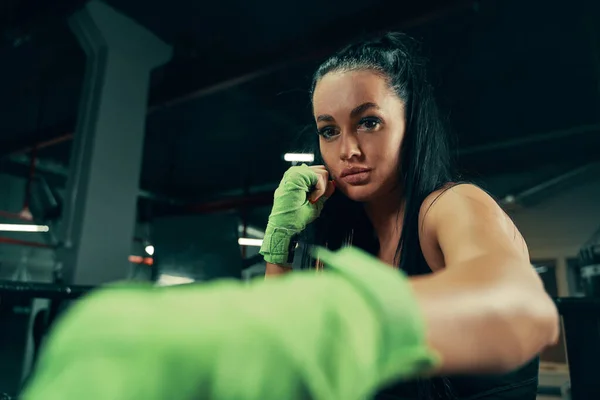 Mujer atlética de pie preparada para luchar con vendajes de boxeo en las manos durante el entrenamiento de caja —  Fotos de Stock