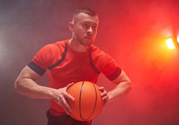 Jonge atleet, basketbalspeler voor te bereiden op het gooien van de bal met achtergrondverlichting en rook op de achtergrond — Stockfoto