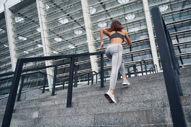 Genç atletik kadın üst kata koşuyor, şehir stadyumunda antrenman yapıyor.