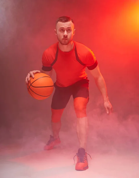 Jonge atleet, basketbalspeler voor te bereiden op het gooien van de bal met achtergrondverlichting en rook op de achtergrond — Stockfoto