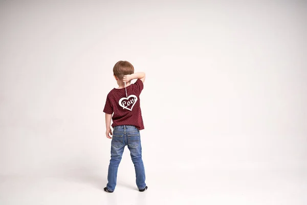 Shot zezadu malého roztomilého chlapce drží dřevěné srdce se znamením láska na minimalistickém bílém pozadí — Stock fotografie