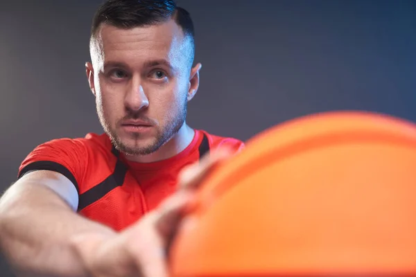 Jonge atletische man bereid voor het gooien van basketbal wijzen naar het doel op koude grijze achtergrond — Stockfoto