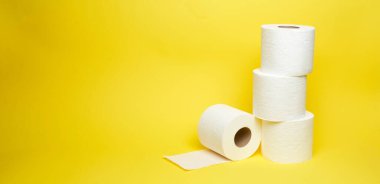 Minimalist sarı arka planda beyaz tuvalet kağıdı ruloları geniş açı