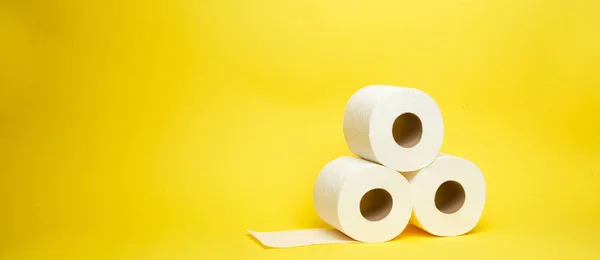 Широкий знімок білого туалету паперових рулонів на мінімалістичному жовтому тлі Стокова Картинка