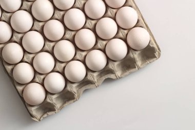 Beyaz arka planda beyaz yumurtaları olan geri dönüşümlü malzemelerden izole edilmiş bir tepsi yumurta. Üst görünüm