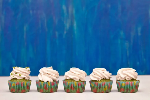Une rangée de cupcakes à la menthe et aux épinards avec confiture de fruits et crème de baies sur le dessus — Photo