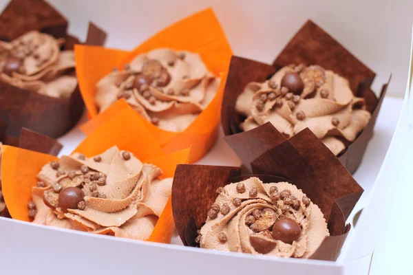 Caixa aberta de cupcakes de chocolate com topo de creme e cobertura crocante em papel sobre um fundo branco — Fotografia de Stock