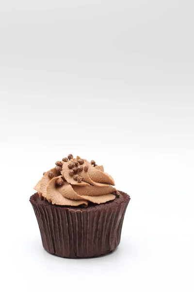 Isolierte Schokoladen-Cupcake mit Sahne-Top und knusprigem Belag auf weißem Hintergrund — Stockfoto
