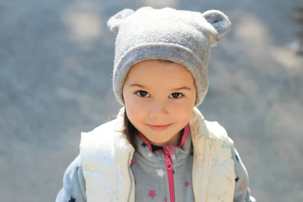 Cheerful smiling white child in a hat with ears and a vest looks up — Stok fotoğraf