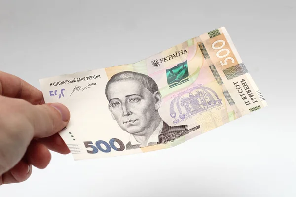 A banknote of 500 hryvnia in a male hand on a white background. Giving a bribe in Ukraine. European money exchange. Ukraine currency. Giving a bribe — 图库照片